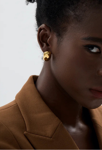 Woman wearing gold earrings with a neutral background